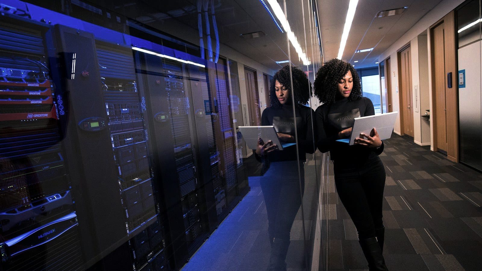Two engineers reviewing a tablet in a lit data-centre aisle