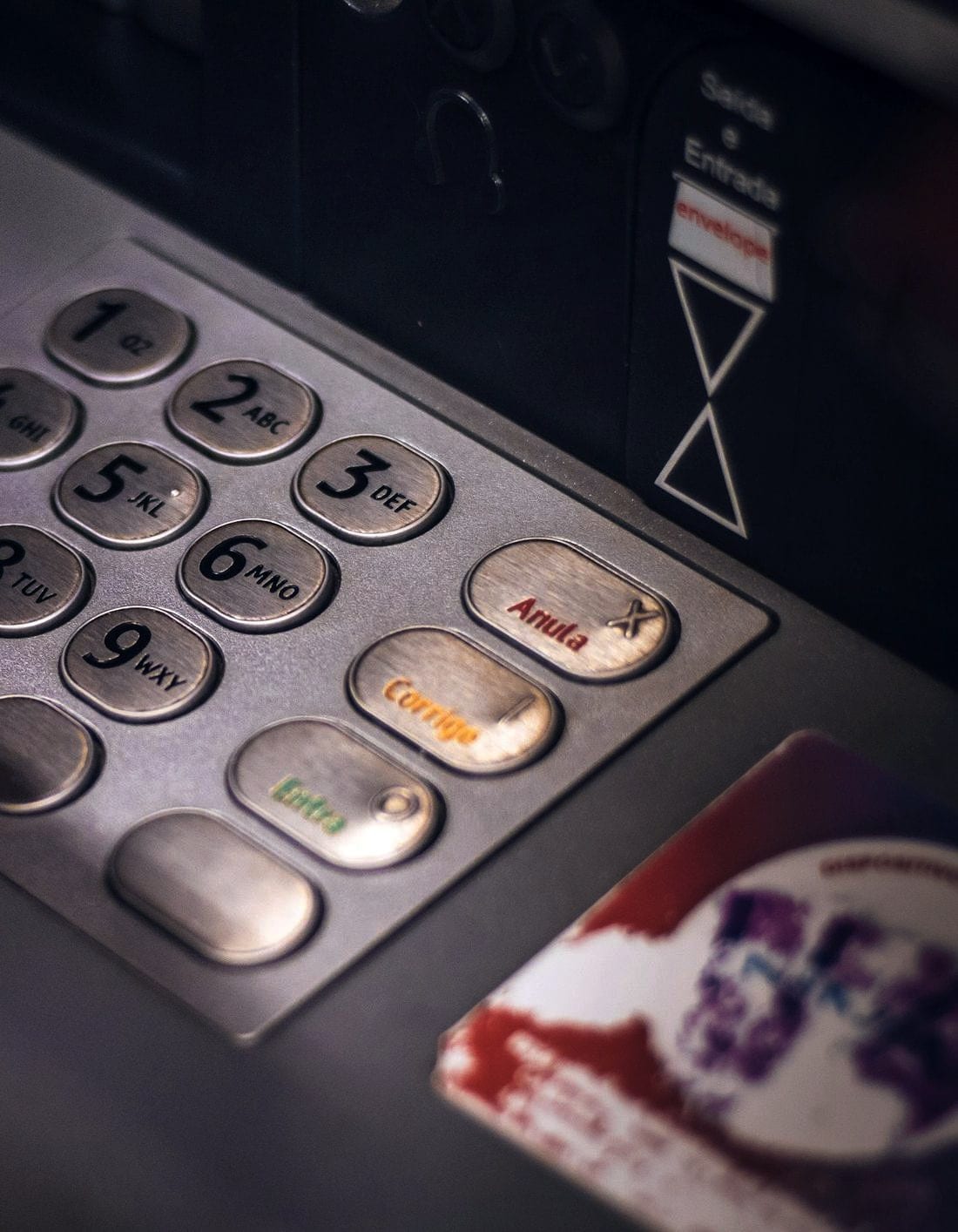 A hand entering a PIN on a worn cash-machine keypad