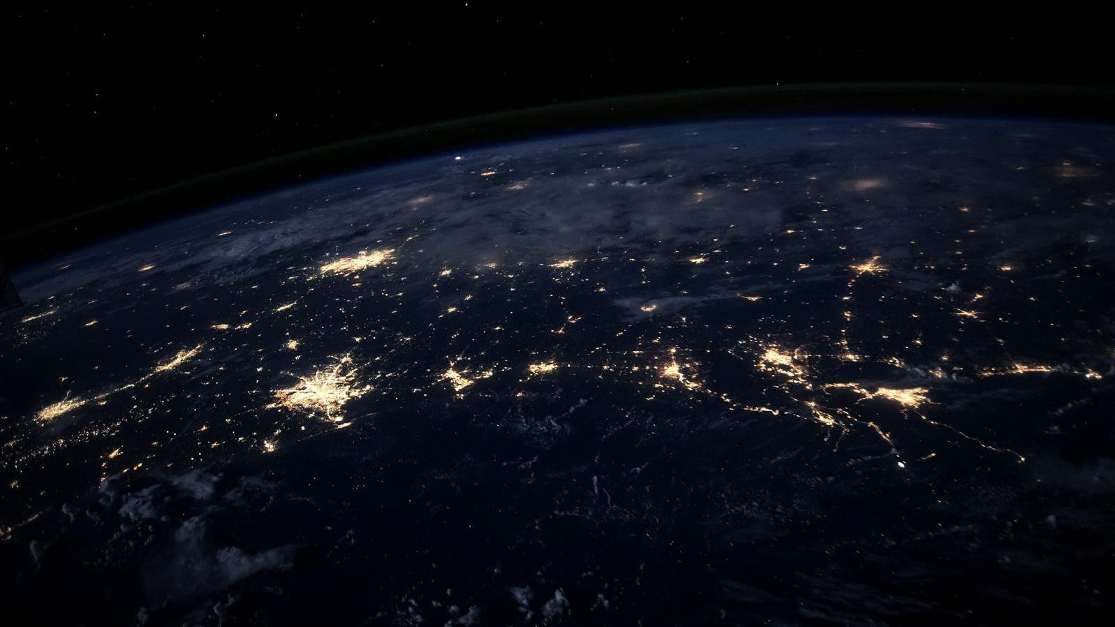 The Earth at night from orbit, city lights along a coastline