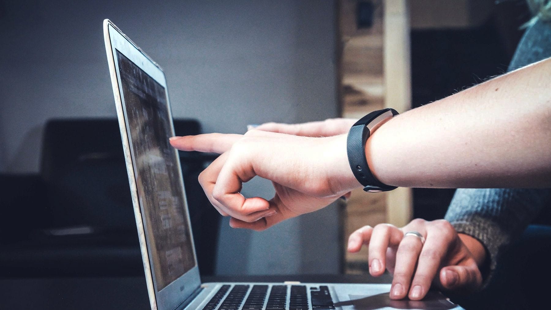 Two people pointing at the same problem on a laptop screen