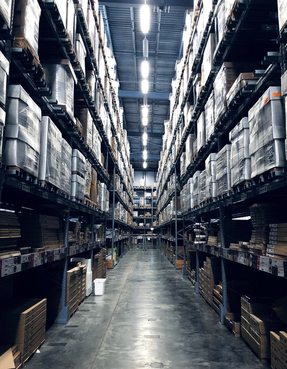 A warehouse aisle running between high racked shelves
