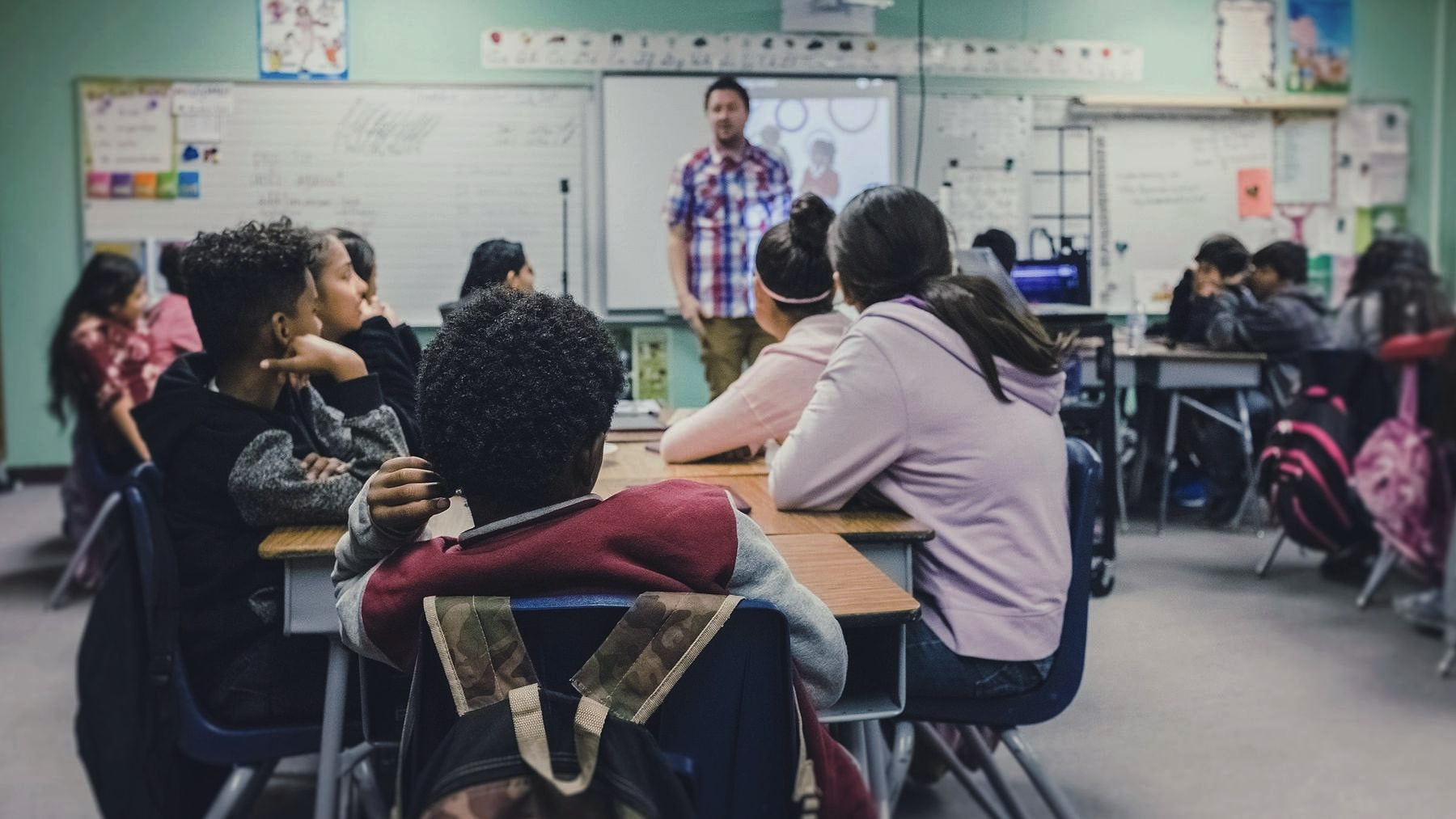A teacher at the board in front of a full classroom