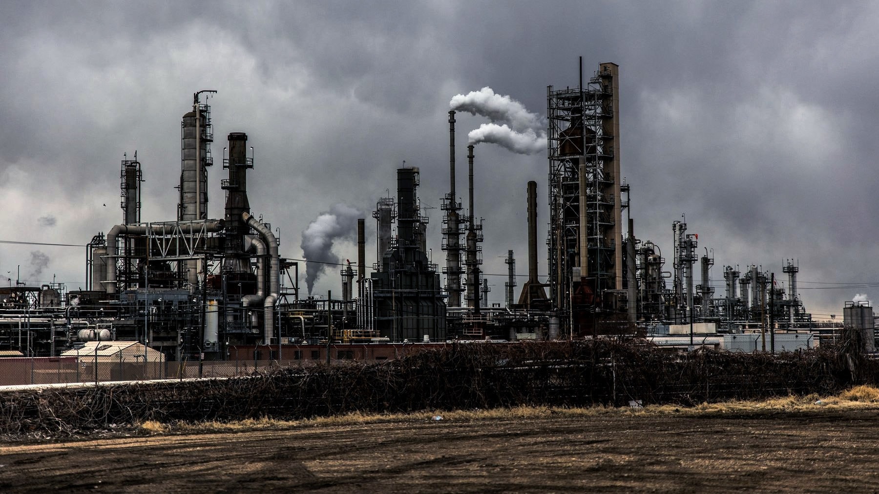 Refinery pipework and stacks running across a flat site