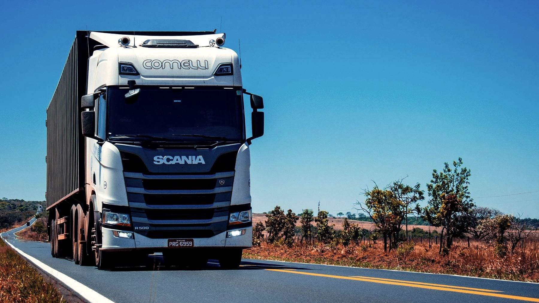 A truck running a straight highway under open sky