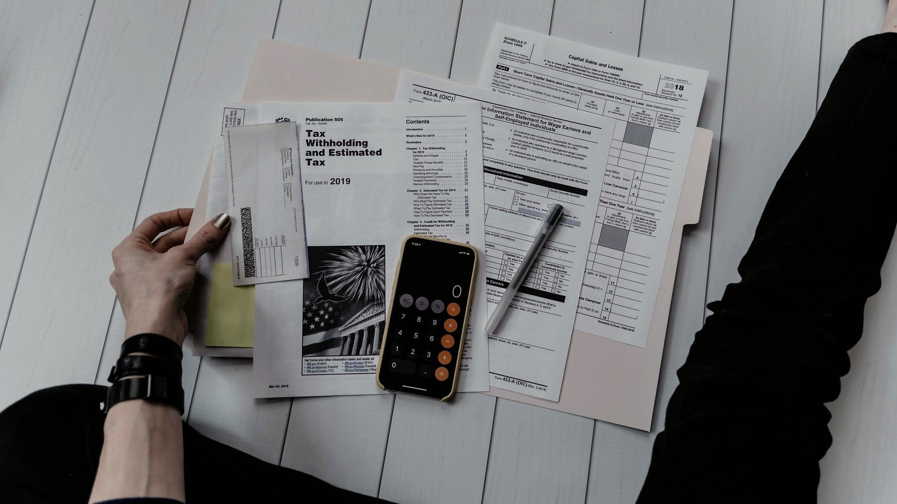 Forms spread across a desk beside a calculator and a phone