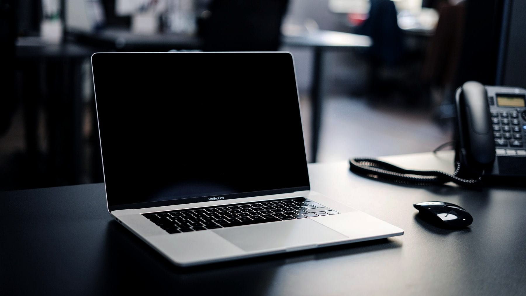 A laptop and a desk phone on an otherwise clear desk