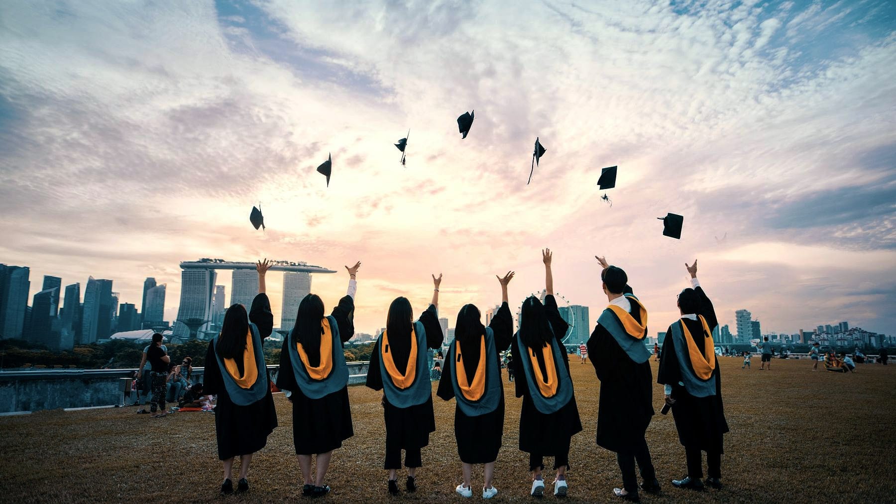 Graduates throwing their caps against an evening skyline
