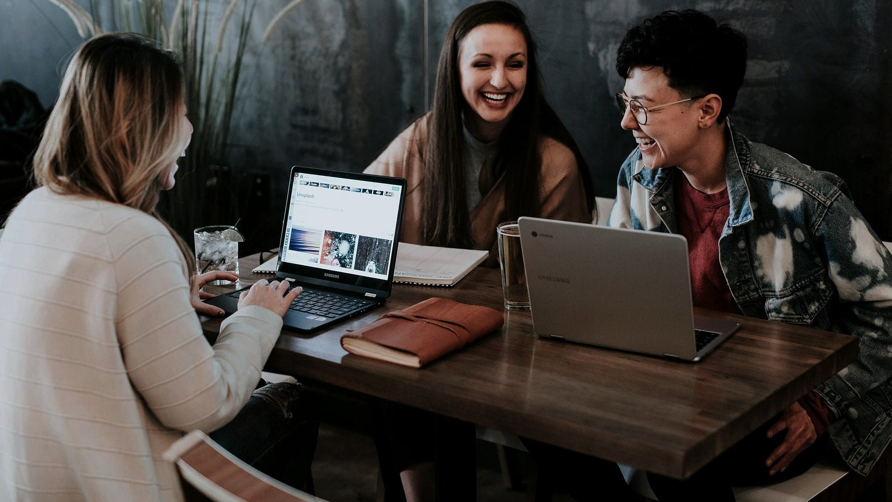 Three students working from one laptop at a table