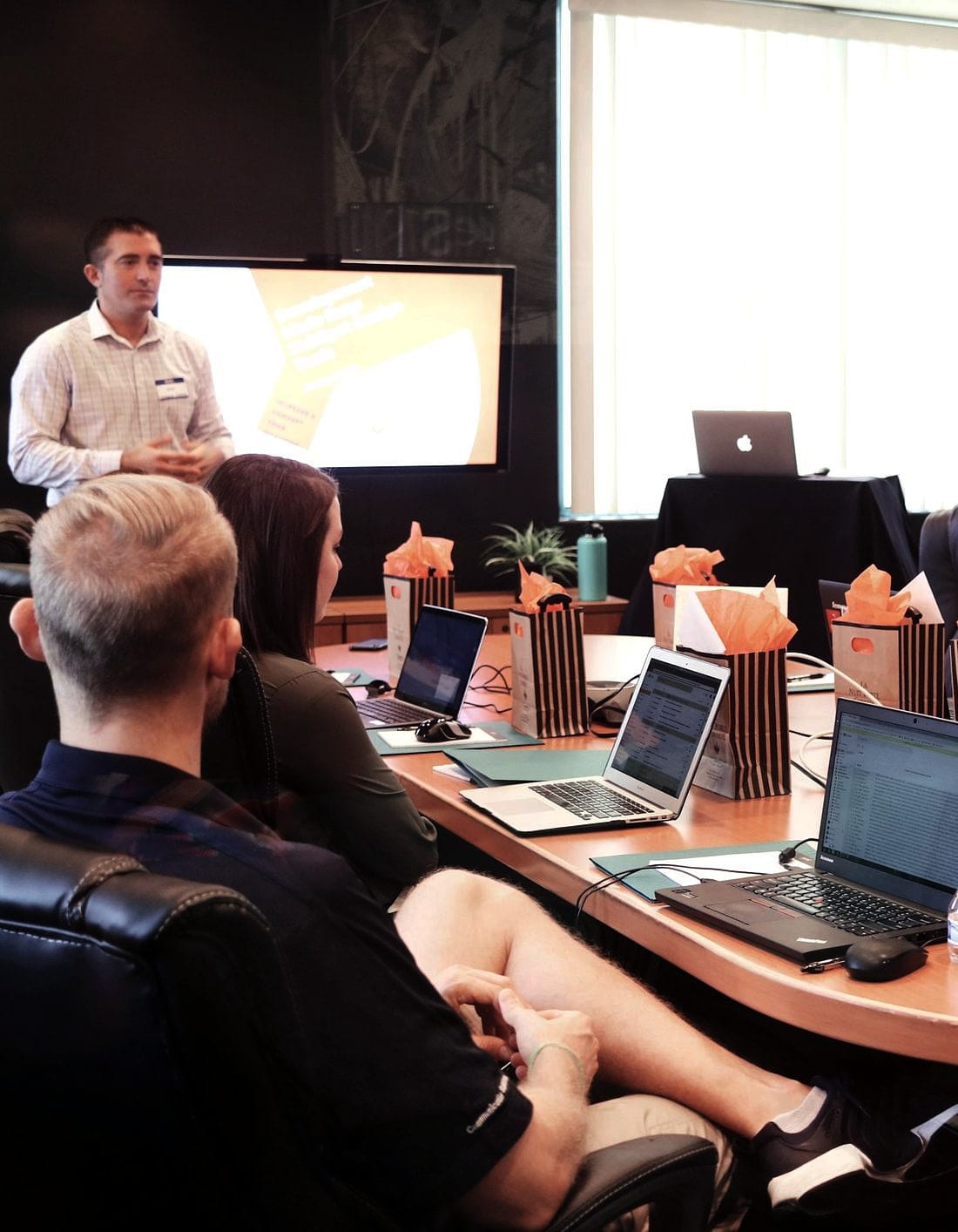 A training room with laptops open and a presenter at the screen