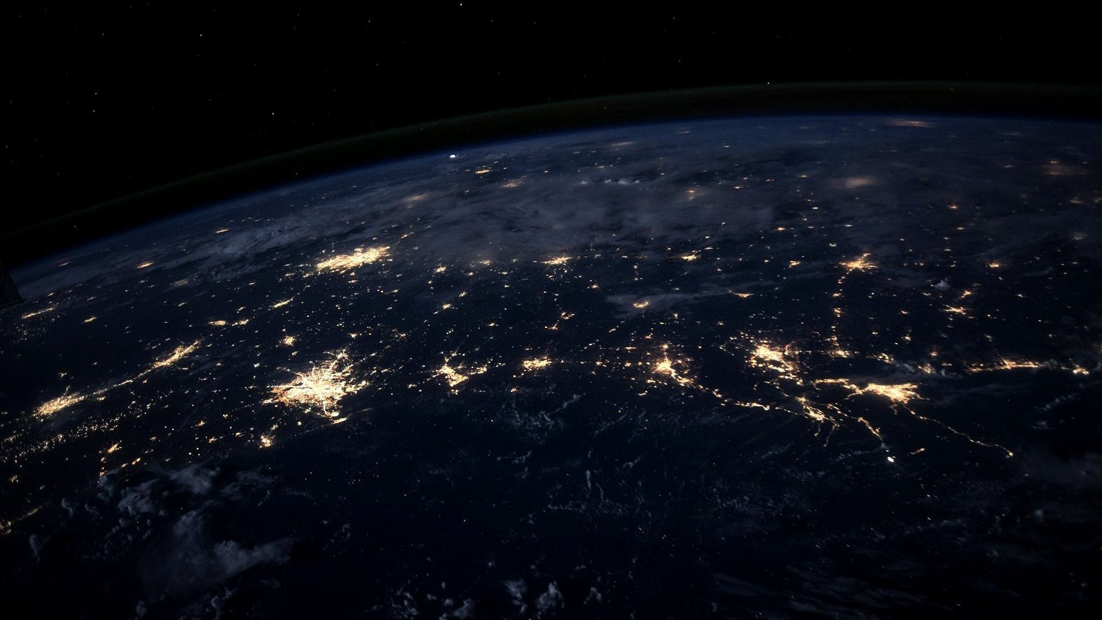 The Earth at night from orbit, city lights along a coastline