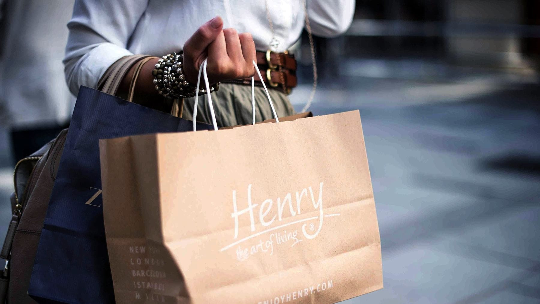 A shopper carrying a paper bag away from a counter