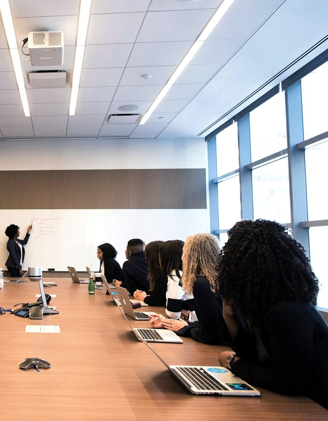 A long table of people following a session in a bright room