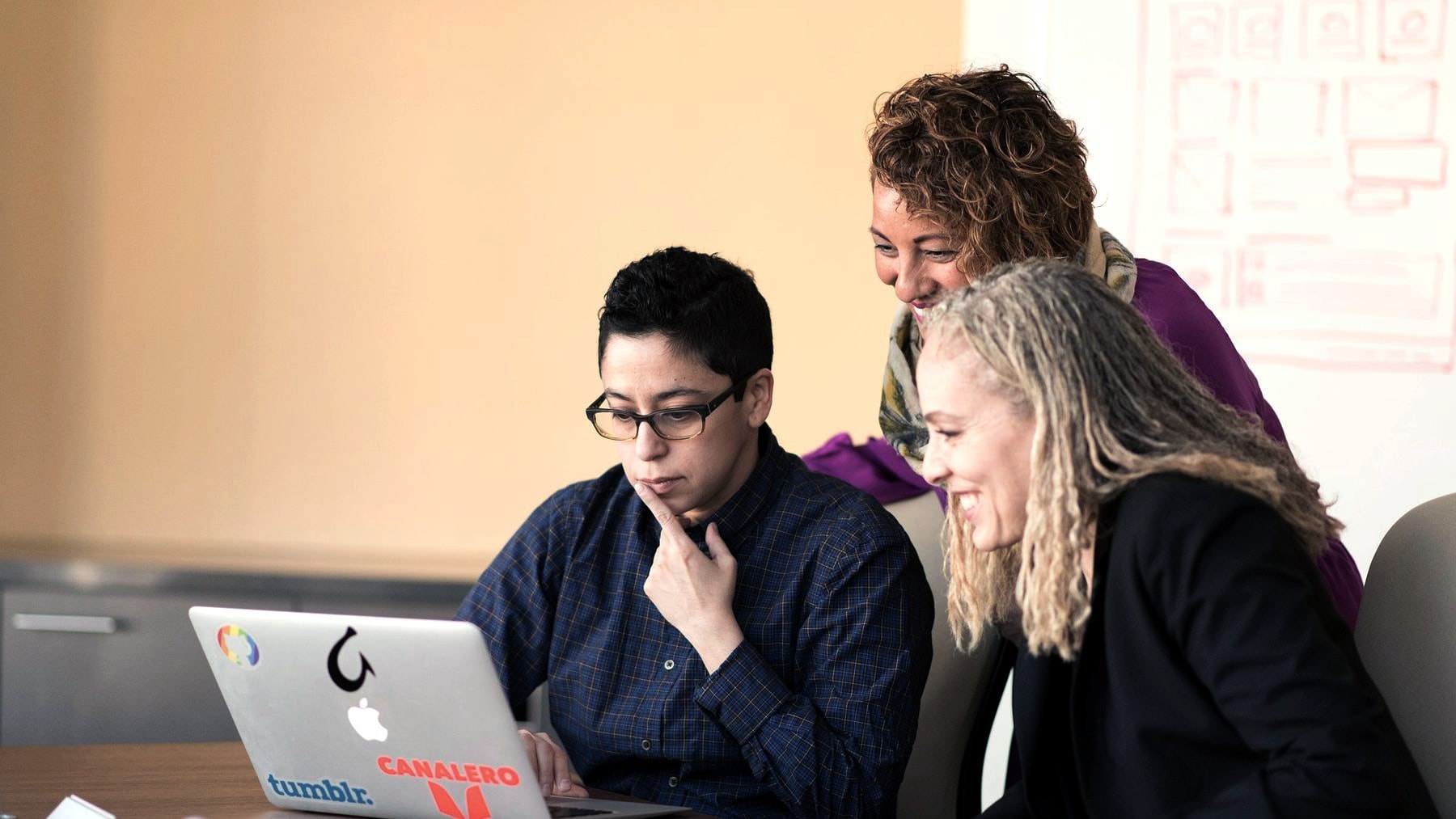 Three colleagues working through something at one laptop