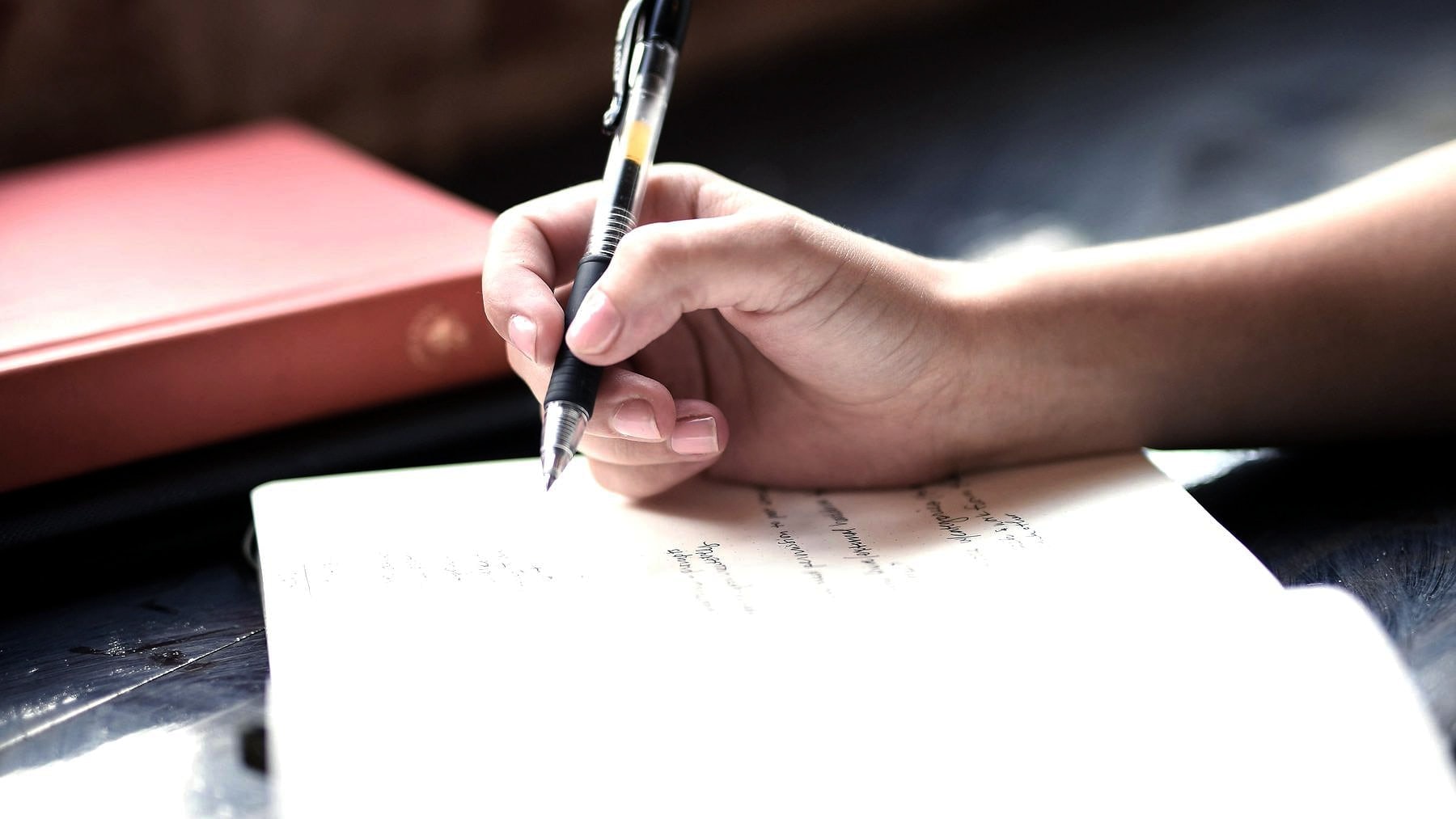 A hand writing the next item down in a notebook