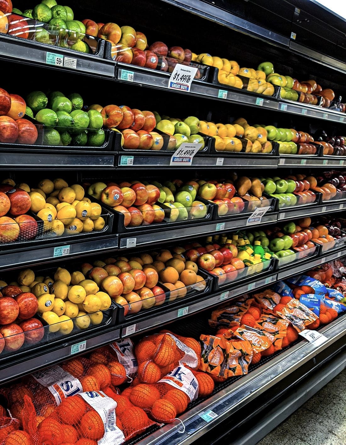 Stocked produce shelves running down a grocery aisle