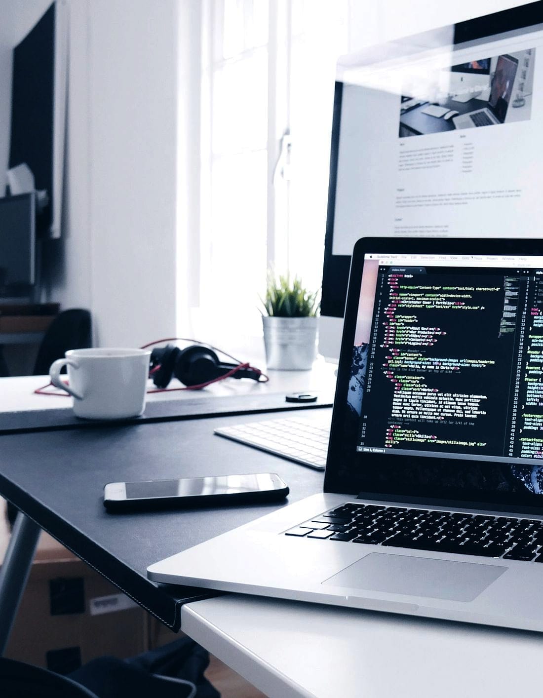 A laptop on a clean desk with code open across both panes